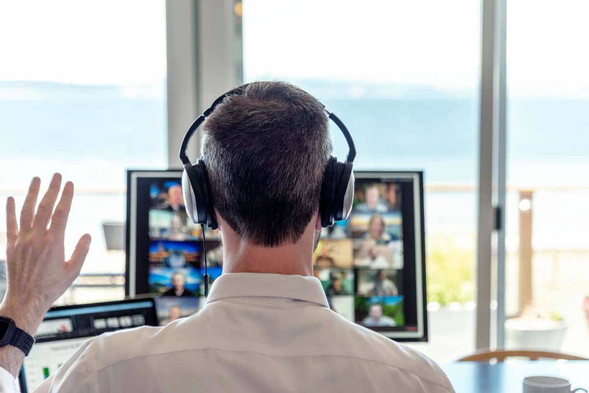 Person wearing headphones in a virtual meeting with multiple participants, representing public meetings that require accessible video content.