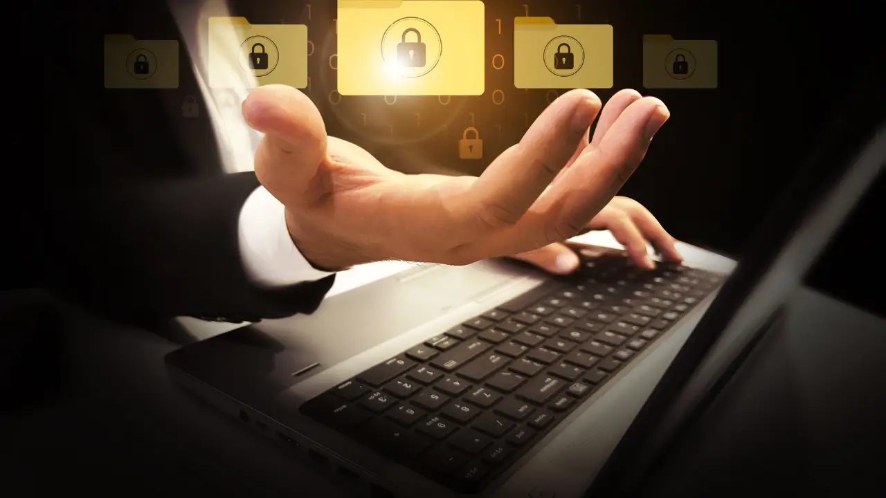 Close-up of a person using a laptop with glowing digital lock and folder icons floating above their hand, representing digital accessibility, privacy, and data security.