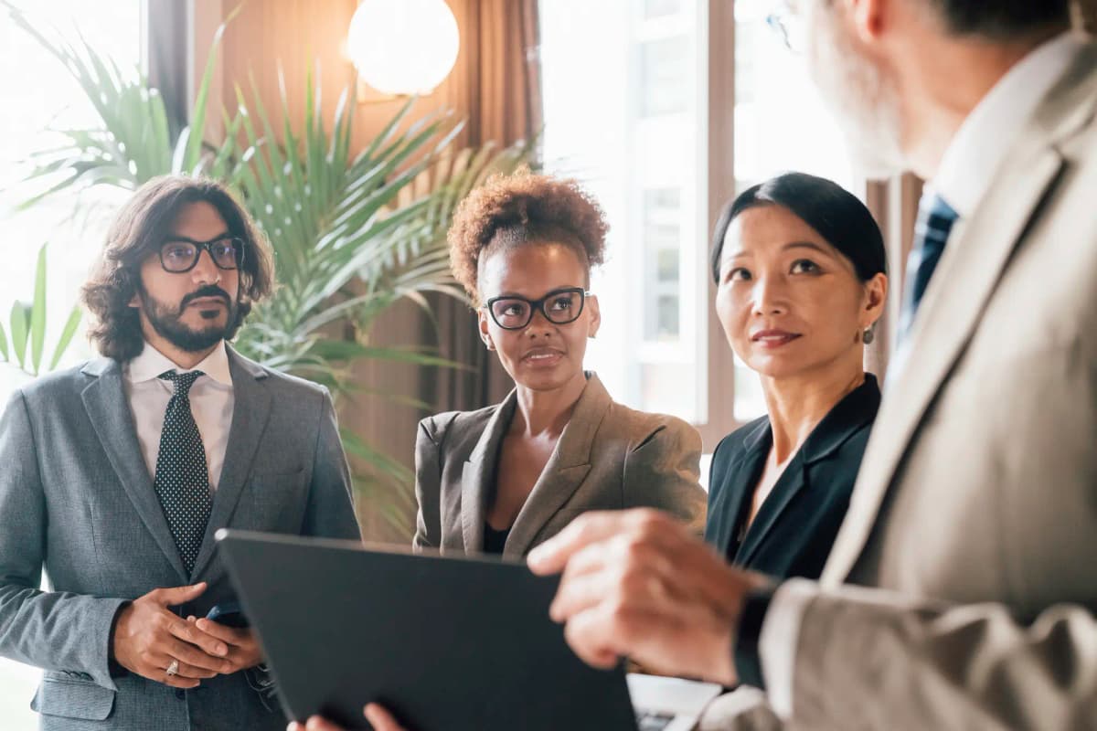 Group of professionals in a meeting reviewing documents and listening to a colleague as decisions are discussed