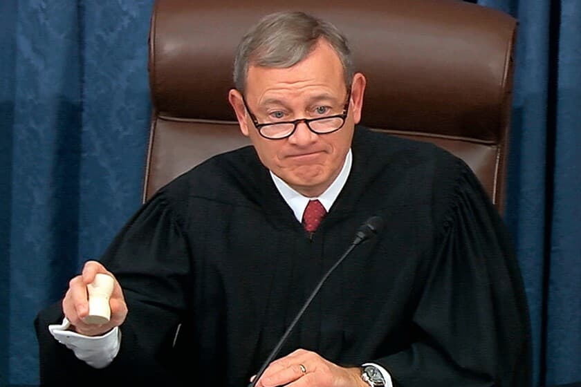 Chief Justice John G. Roberts, Jr., wearing a black judicial robe and red tie, seated at the bench, holding a gavel with one hand and looking forward with a slight expression of emphasis. Image likely sourced from official government video footage or public hearing broadcast.