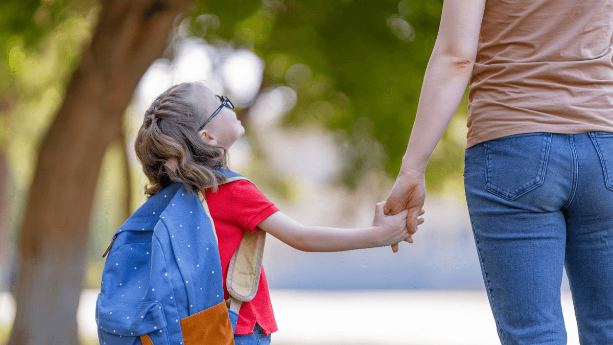 Child with glasses holding a caregiver&rsquo;s hand on the way to school, representing parental advocacy in disability rights education after the A.J.T. v. Osseo ruling.