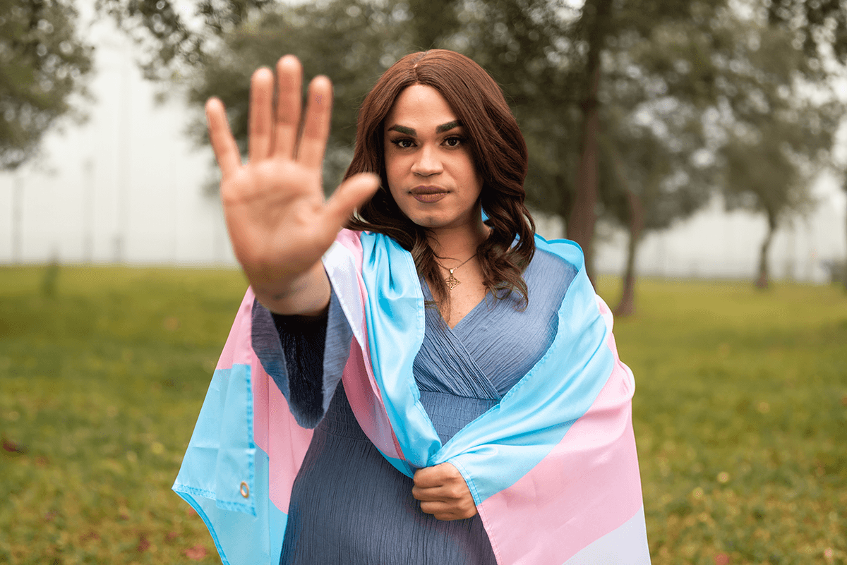 Trans Woman Doing Stop Sign and Holding Trans Flag.