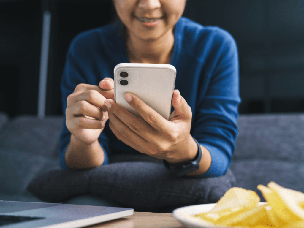 Resident accessing a local government website on a smartphone, seated casually with a laptop nearby.