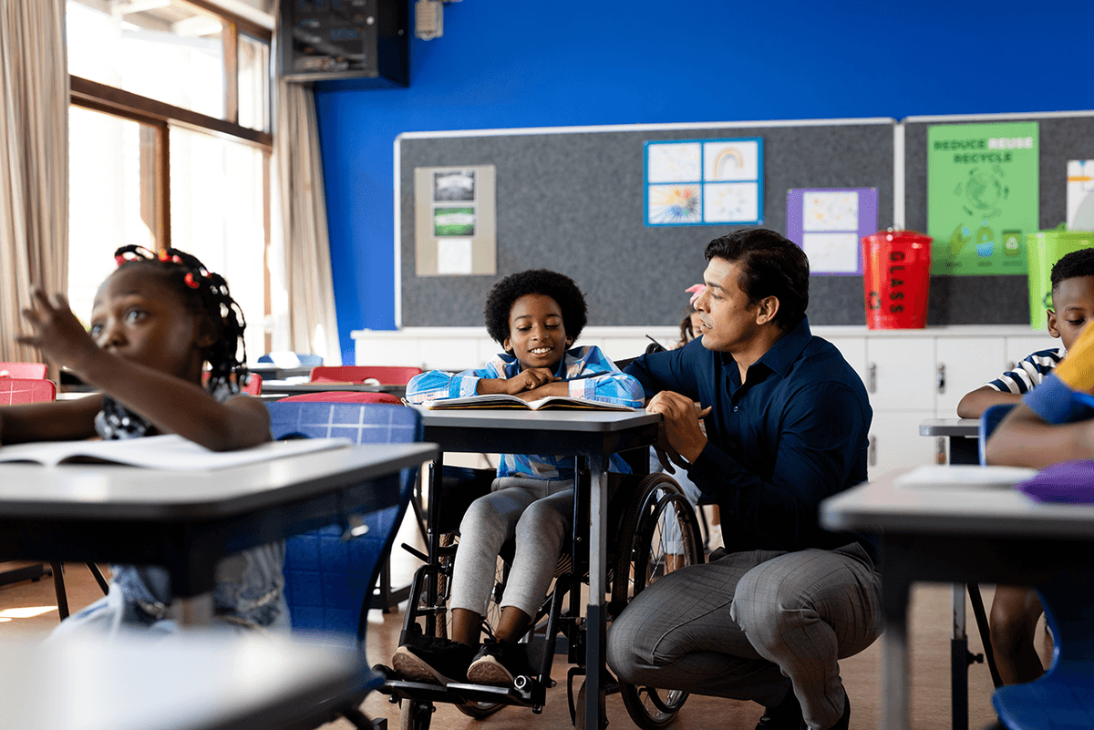 A teacher assists a student using a wheelchair in a classroom, promoting inclusive education and accessibility.