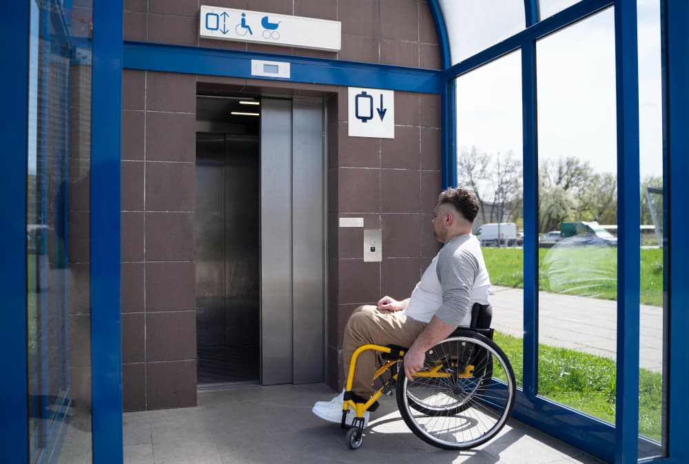 A Man in a Wheelchair Waits in Front of an Elevator