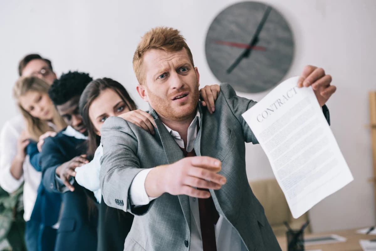 Exhausted zombie-like businesspeople standing in row, the first one holding a hand copy of a contract