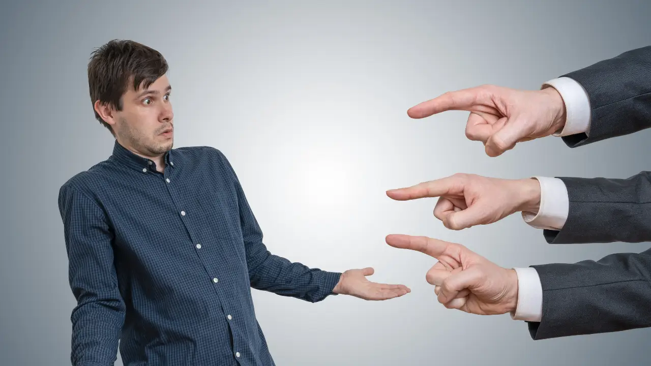 Man in suit looking confused as three hands point toward him