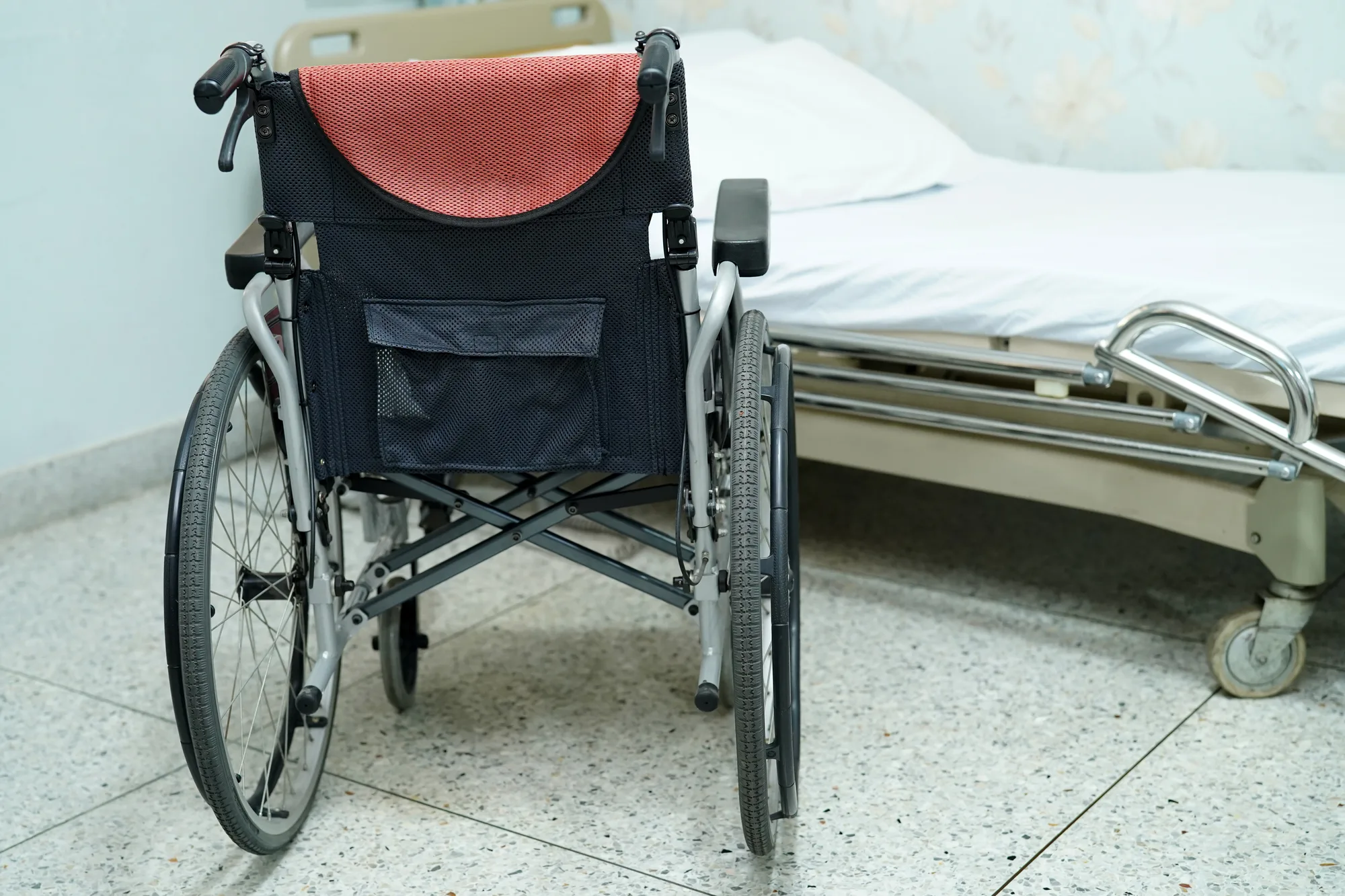 Empty wheelchair beside high hospital bed