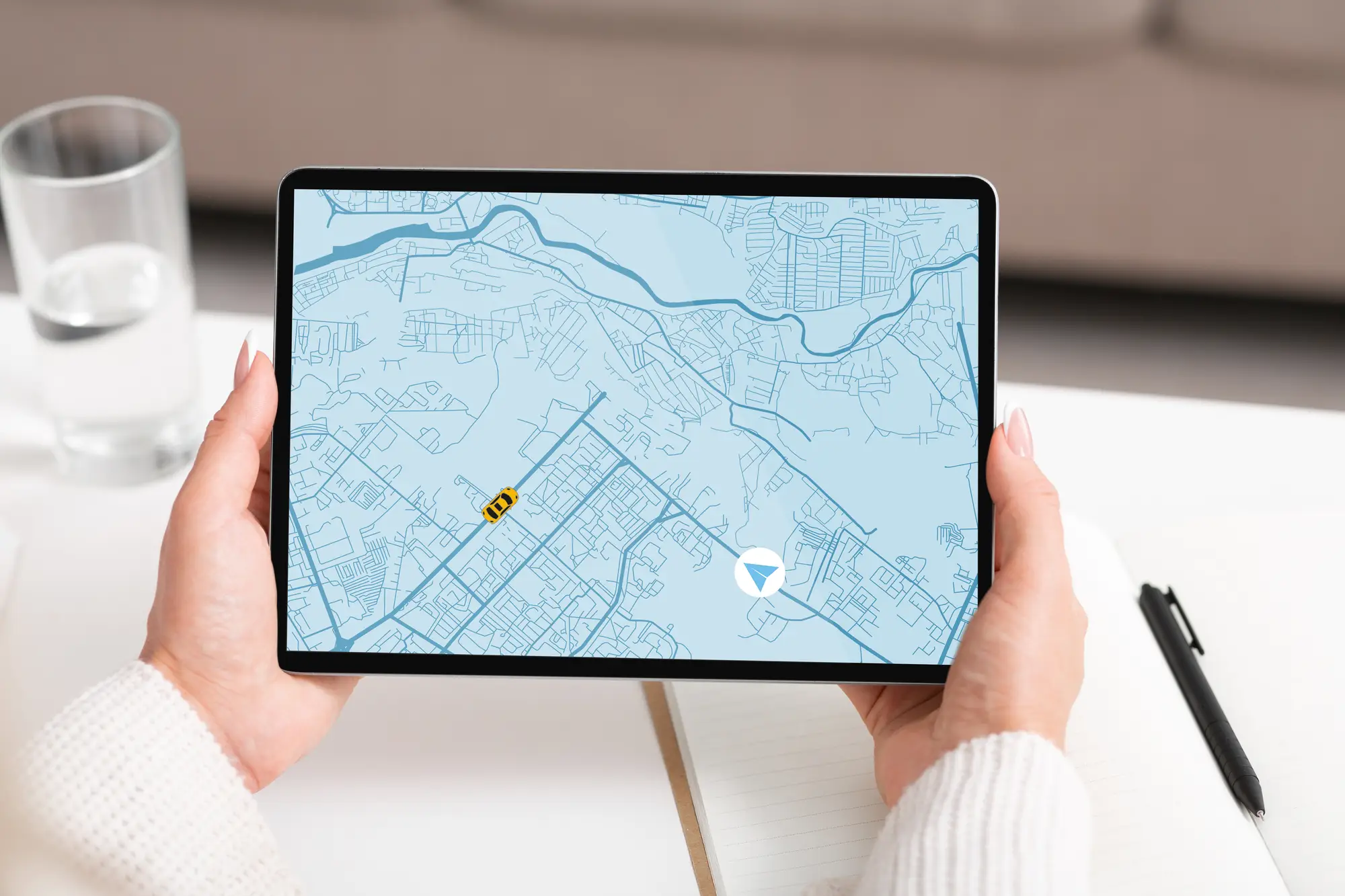 Person holding a tablet displaying a digital map with roads, locations, and navigation markers.