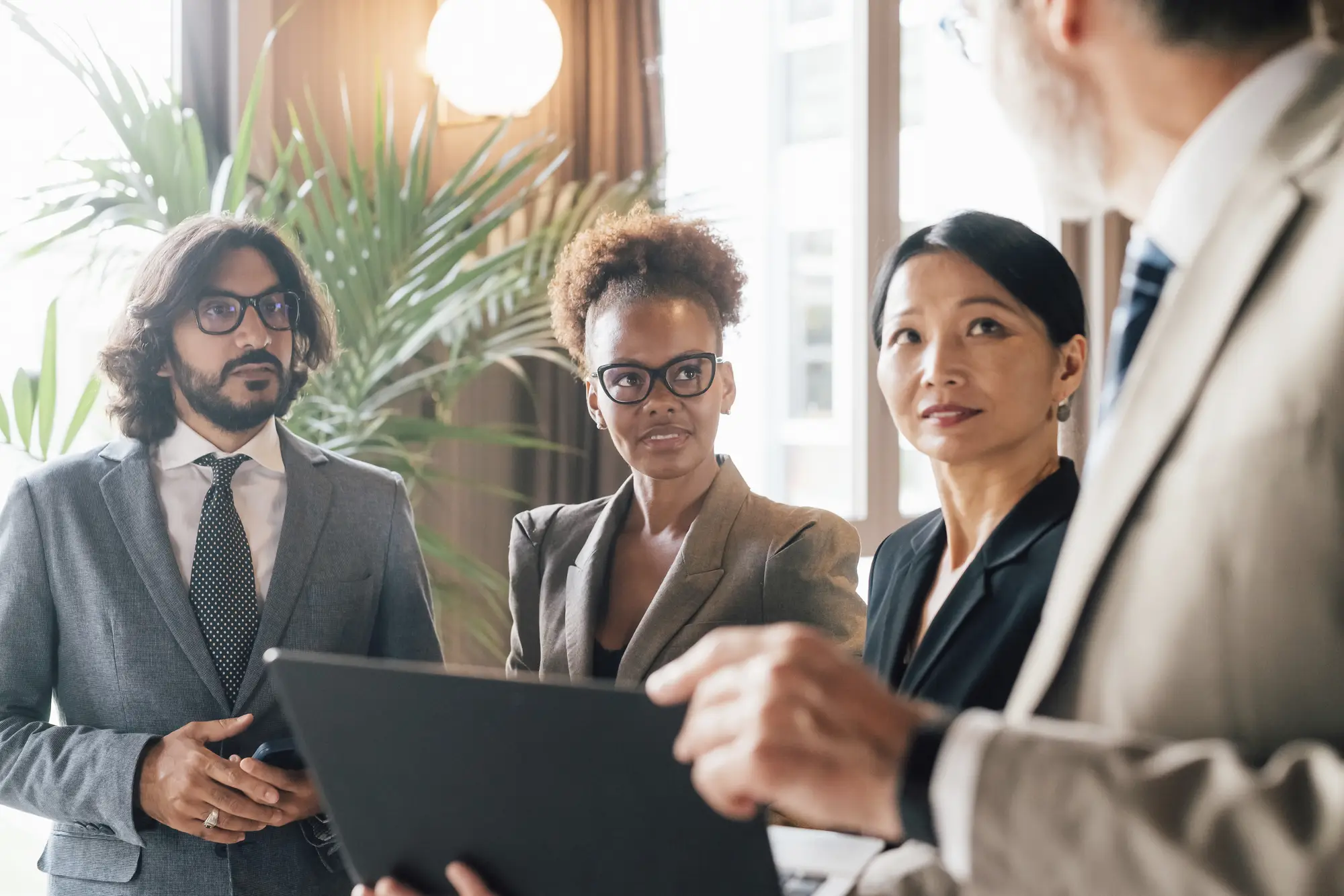 Group of professionals in a meeting reviewing documents and listening to a colleague as decisions are discussed
