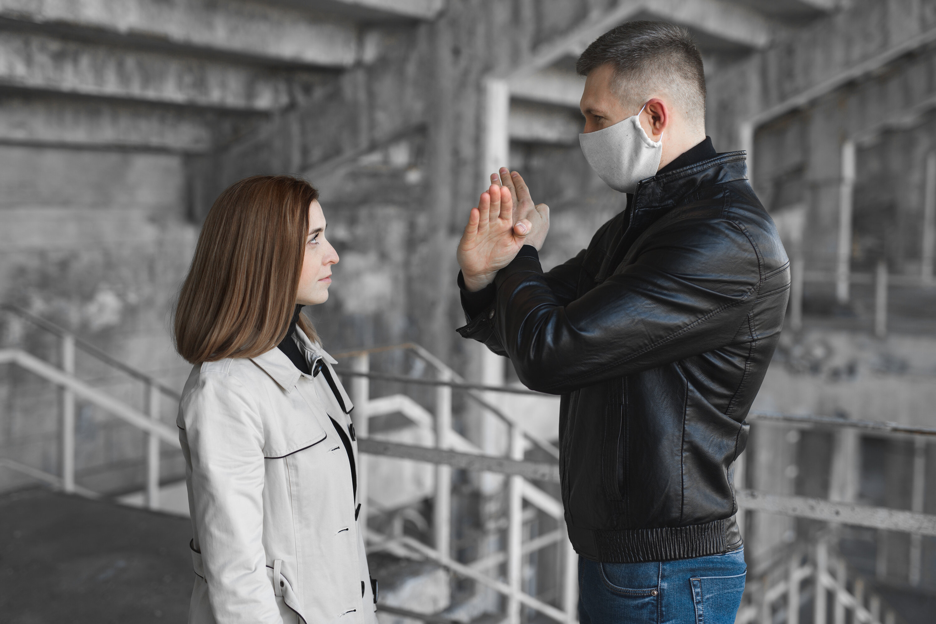 A masked man uses sign language to communicate with a woman, highlighting COVID-19 mask barriers for the Deaf community.