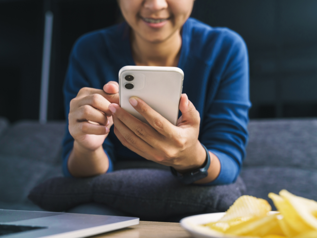 Resident accessing a local government website on a smartphone, seated casually with a laptop nearby.