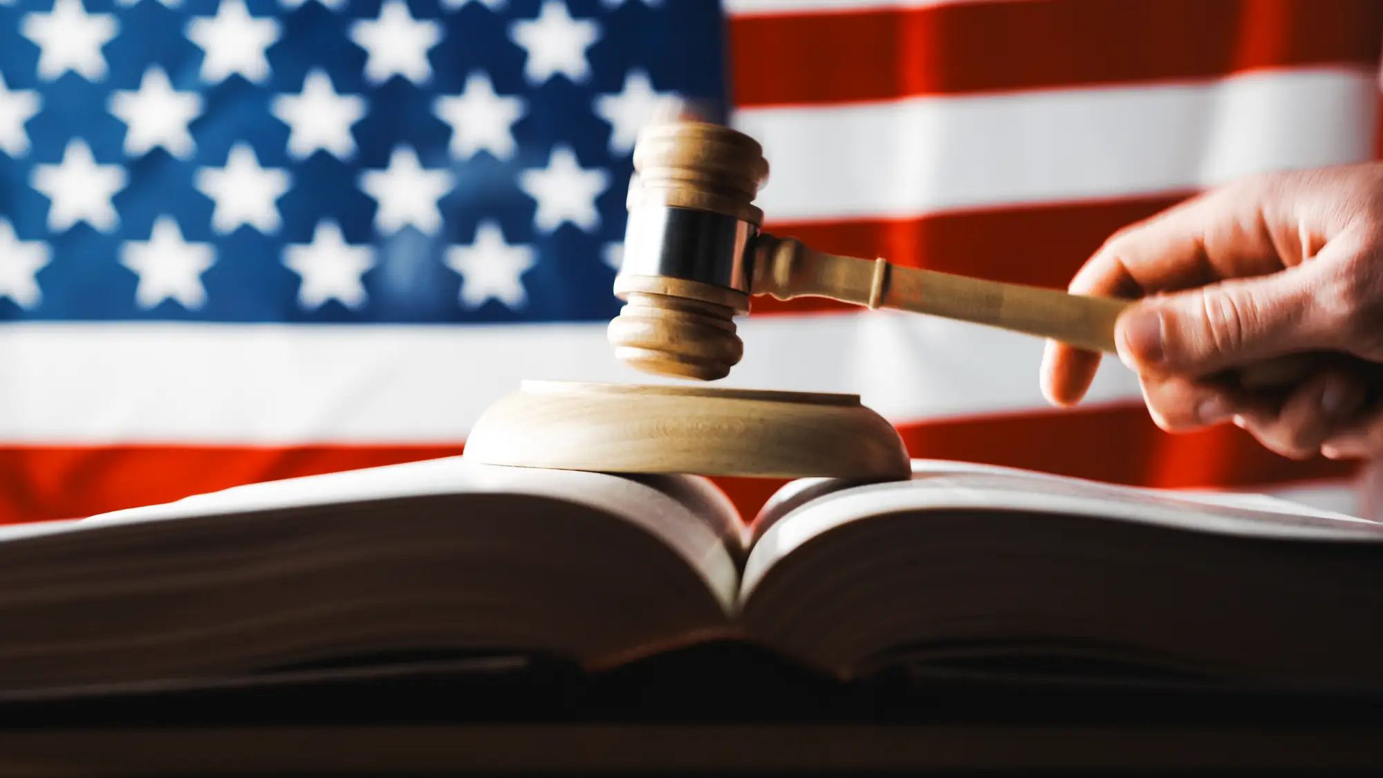 Judge's gavel resting on an open law book with the United States flag in the background representing federal law and ADA Title II regulations