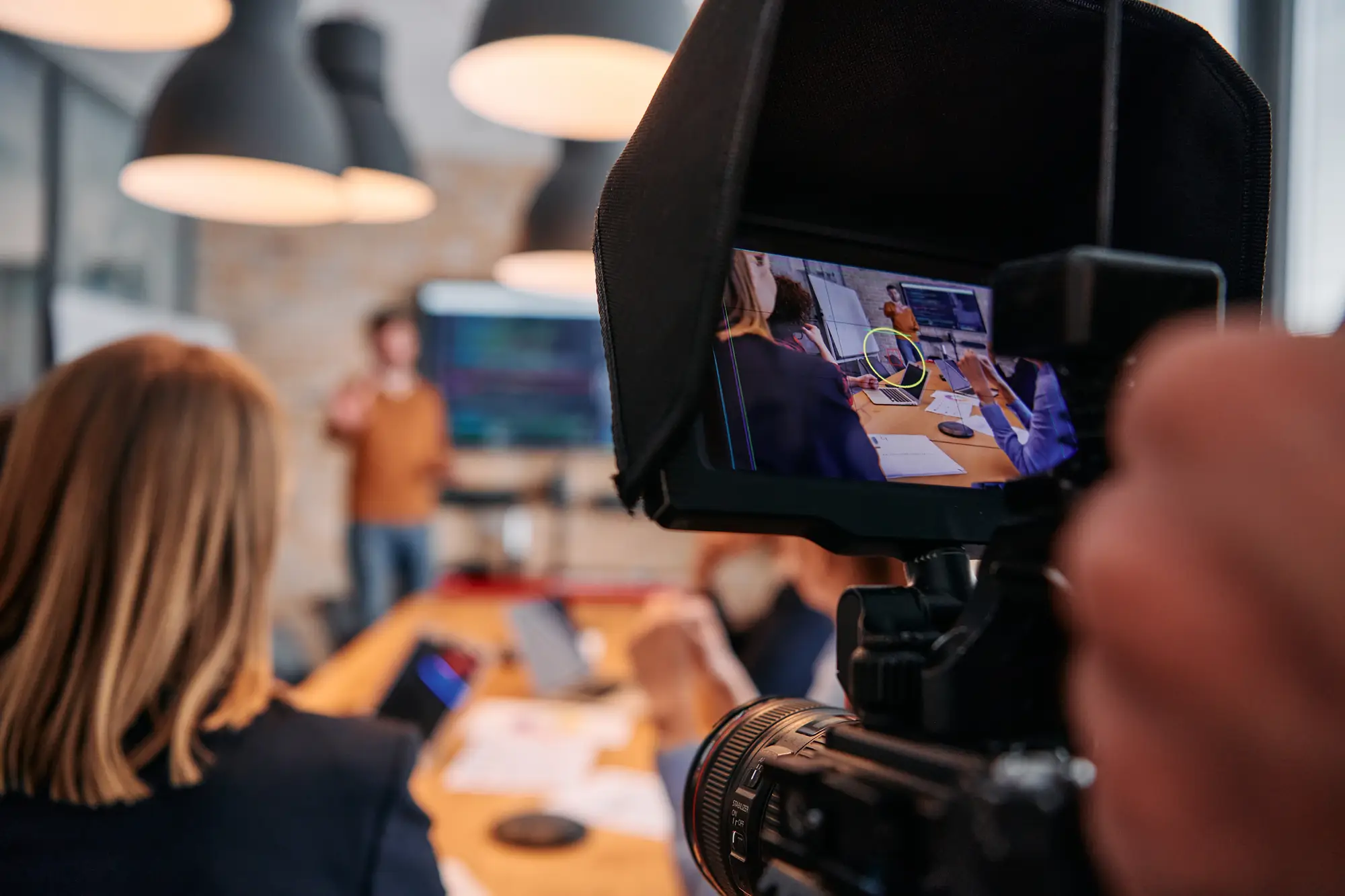 Camera filming a government meeting with presenter and staff, representing creation of public facing video content requiring accessibility.
