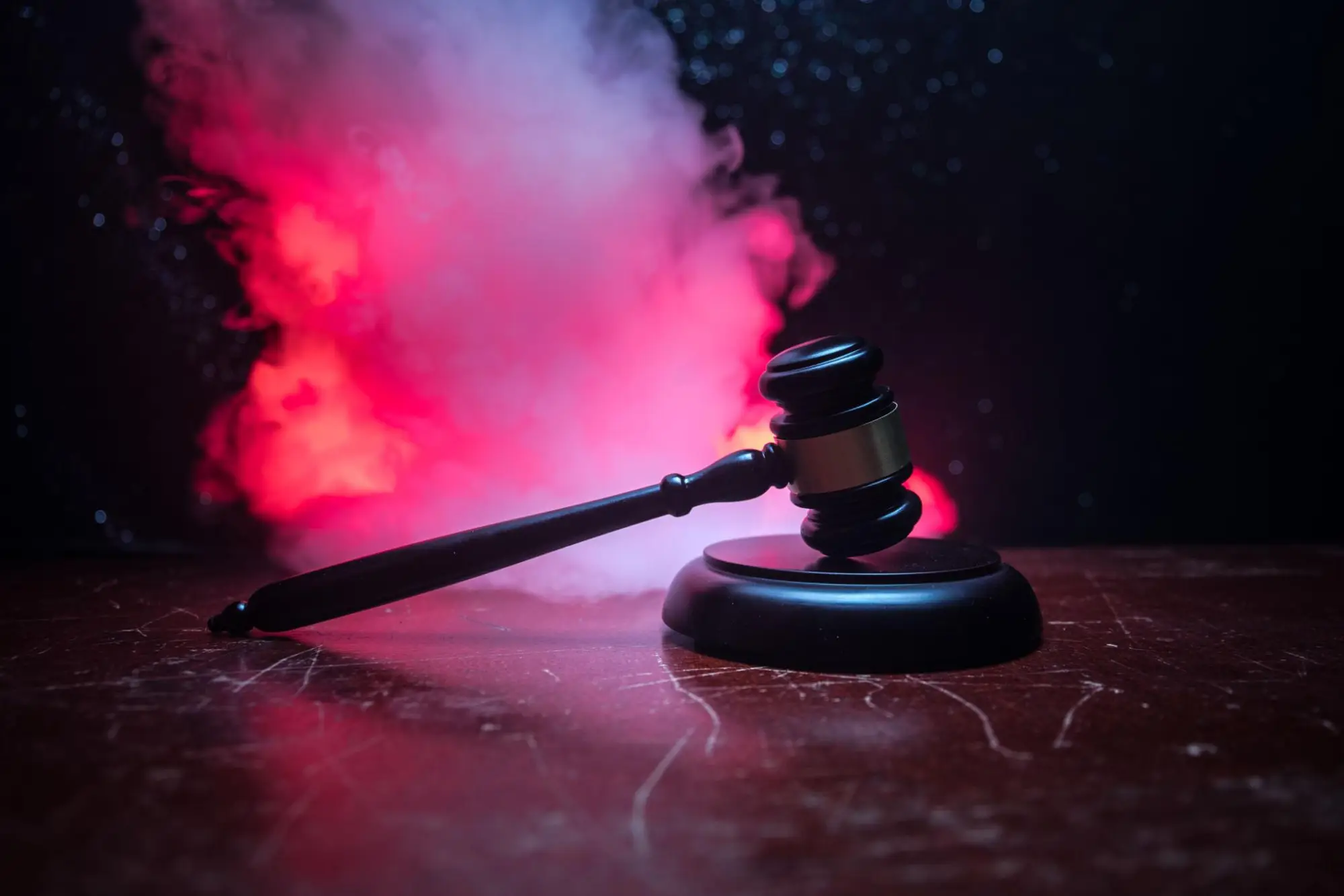 A gavel on a desk with red smoke behind it, representing legal urgency and ongoing digital accessibility barriers under ADA Title II.