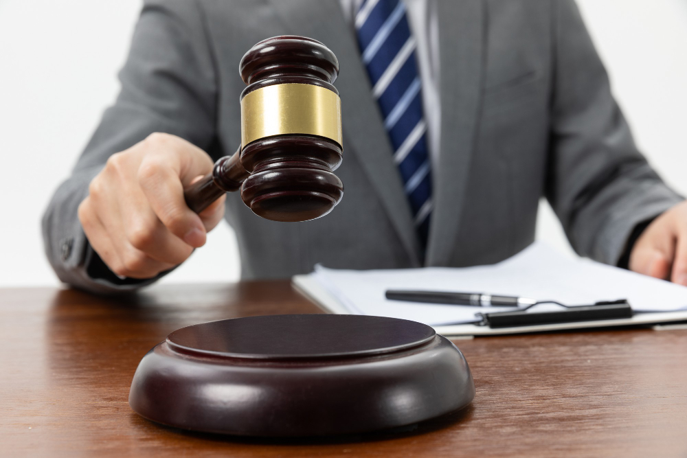 Person in suit holding judge's gavel over sound block at desk