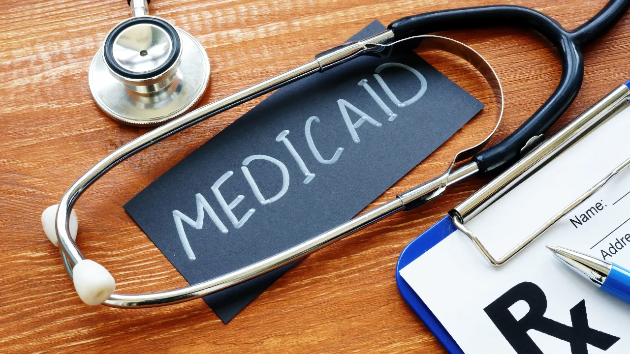 Stethoscope and clipboard with Medicaid card on wooden desk