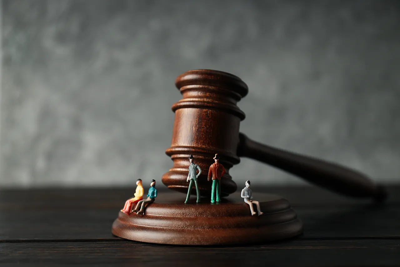 Wooden judge's gavel with miniature figures standing on its base